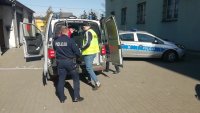 policjanci z zatrzymanym przy radiowozie.
